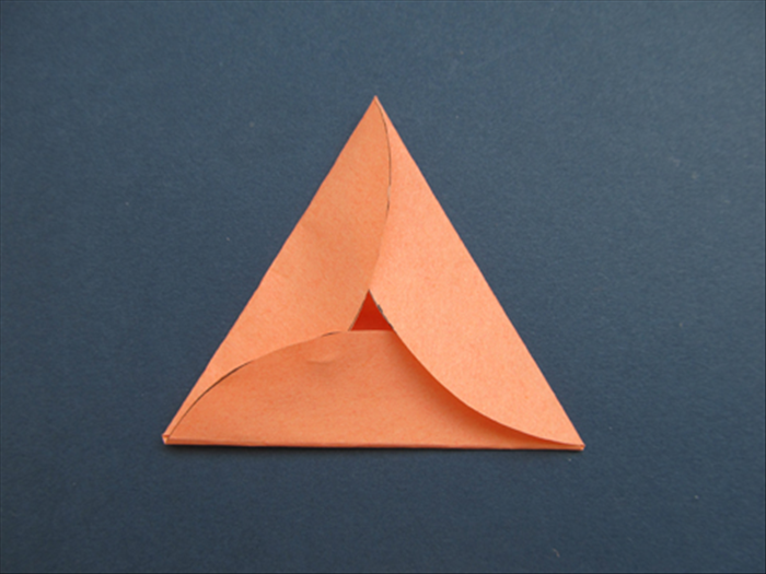 Unfold and remove the scrap paper triangle.
Refold along the creases of the triangle and overlap the right side of each corner. 

Your Purim card in the shape of a Hamantaschen cookie is folded!

Unfold, write your message inside, refold and add your message on the outside.
