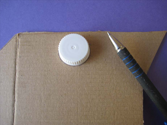 Draw a circle around the small bottle cap on the cardboard.