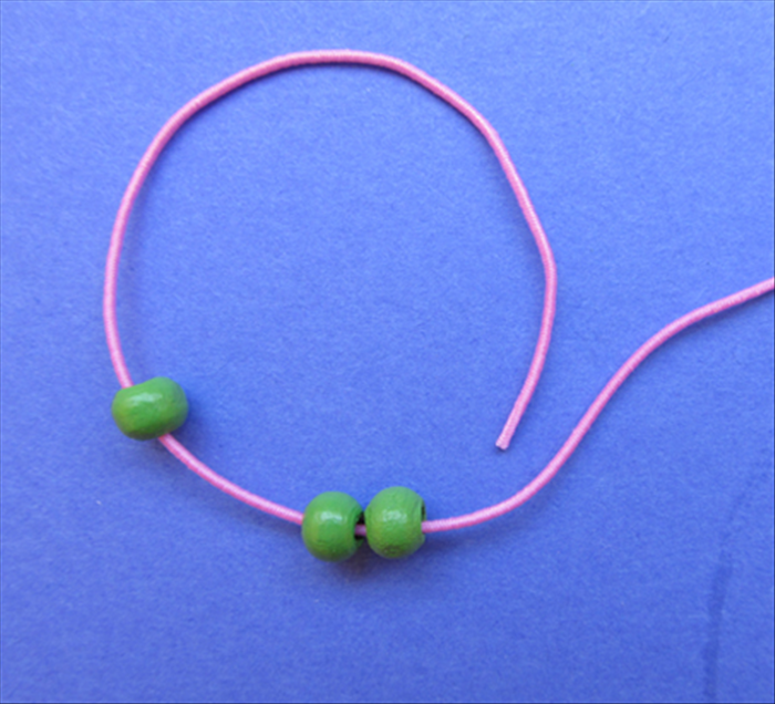 Take the left end of the string and insert it into and through the 2 beads from the right side.
