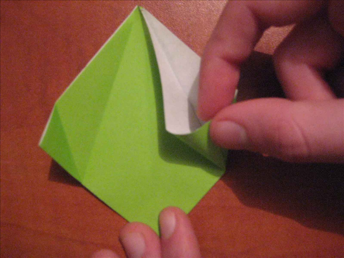 Lift up the right top layer and fold it along the diagonal crease to align the edge with the center crease.
Swash down the triangle that pops up. 

Repeat on the left side.
