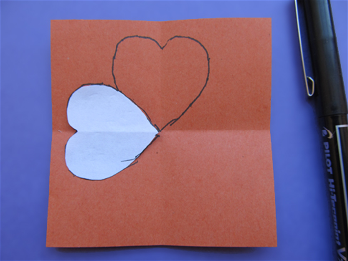 Align the heart to the horizontal crease with the point touching the center

Trace the outline of the heart shape
