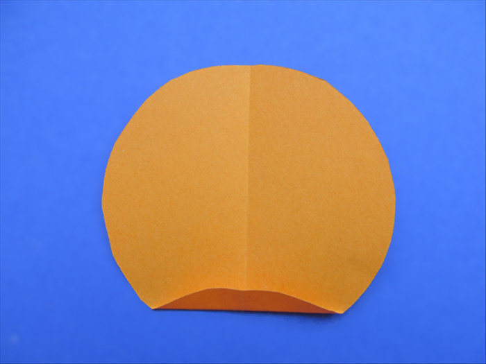 Rotate the circle so that the crease is vertical

Make a small fold at the bottom of the circle. Use the crease line as a guide to keep the fold straight.
