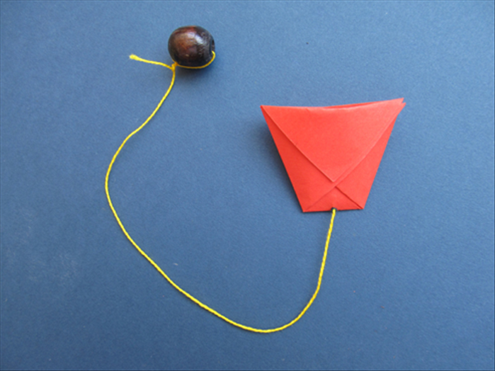 Materials:
1 square piece of paper
String about 2 and a half times the length of the side of the square paper

1 bead
A pointed object such as a toothpick or point of a pen
Scissors to cut the string
