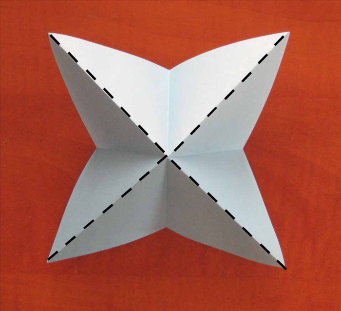 Flip the paper over to the other side.
Pinch  all the diagonally folds. Continue to squeese them and the horizontally folds will fold inward.
