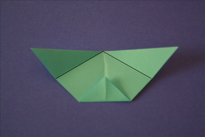 Fold the top corners down at an angle until they touch the corners of the triangle at the bottom 