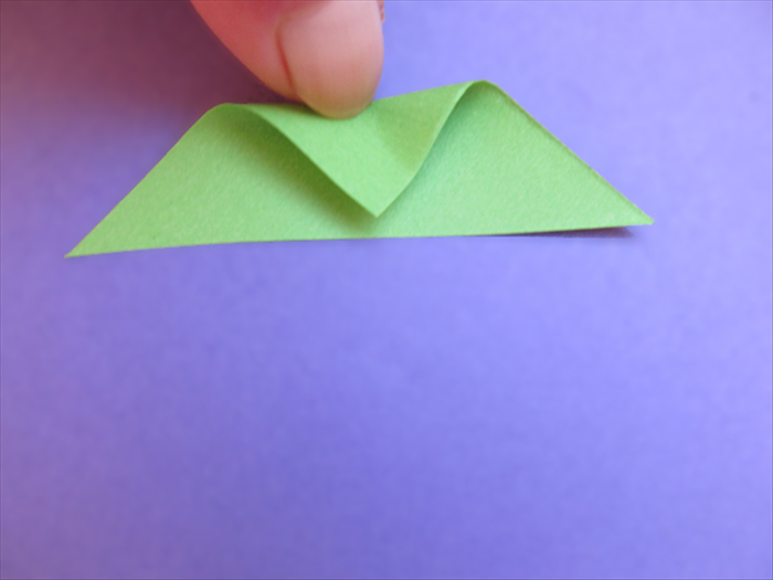 Take the 4 unfolded triangles and bring the top point down as if you were going to fold it in half.
Do not fold. Pinch the edge to mark the halfway point.
