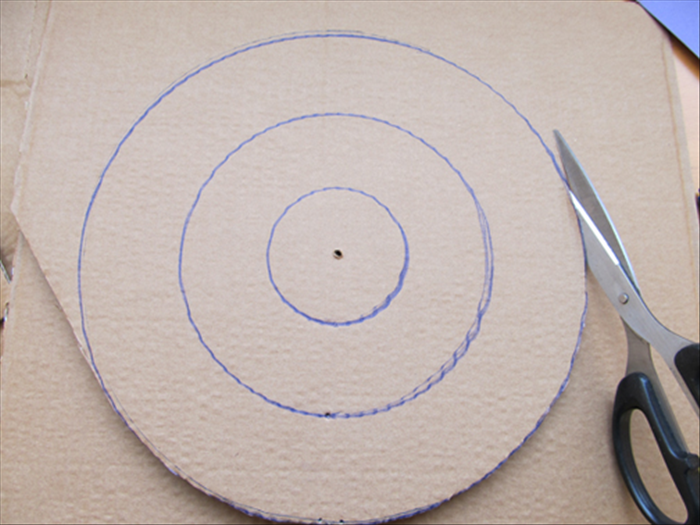 To draw circles on cardboard you will need:
Pen or pencil
Screw with sharp point
1 paper fastener
Cardboard to draw on 
Cardboard strip about 1.5 inches larger than the radius of the circle you want to draw
