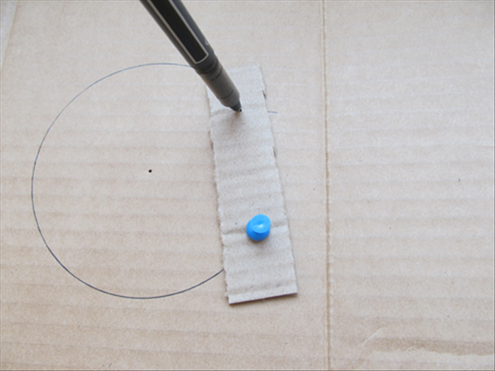 Put the pen point through the hole it was in.
 Rotate the cardboard strip until it reaches the line of the circle and make a mark there
