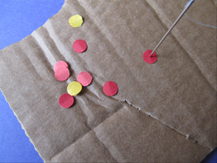 Place circles on the corrugated cardboard.
Punch the threaded needle as close to the center of the circles as you can.