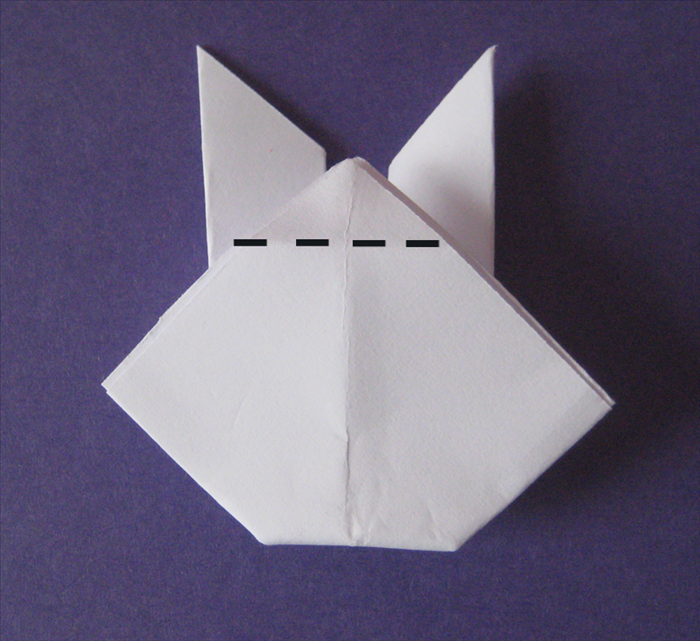 Flip the paper over to the back side.
Fold the top middle point down to the back as shown in picture.

This is the back of the rabbit.
Flip it over to the front side.