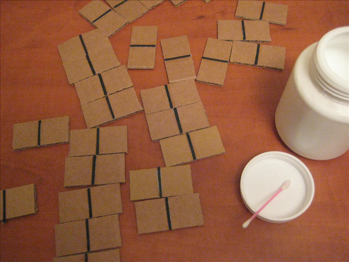 Glue the dark strips to the center of the cardboard rectangles. Use the marks you made for their placement.