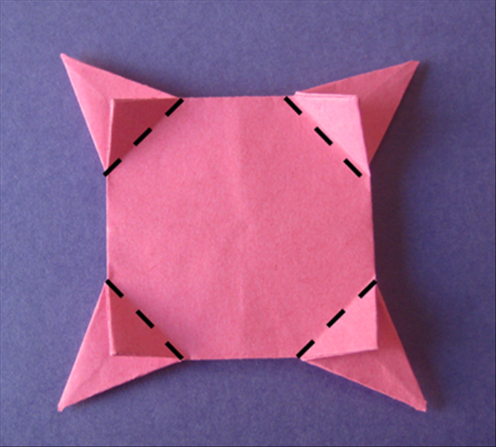 Flip the paper over to the back side.
Fold the small flaps towards the center.
