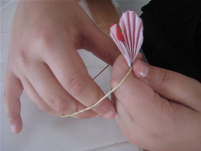 Hold the folded circles together and wrap a rubber band or string around the center to hold them in place.
