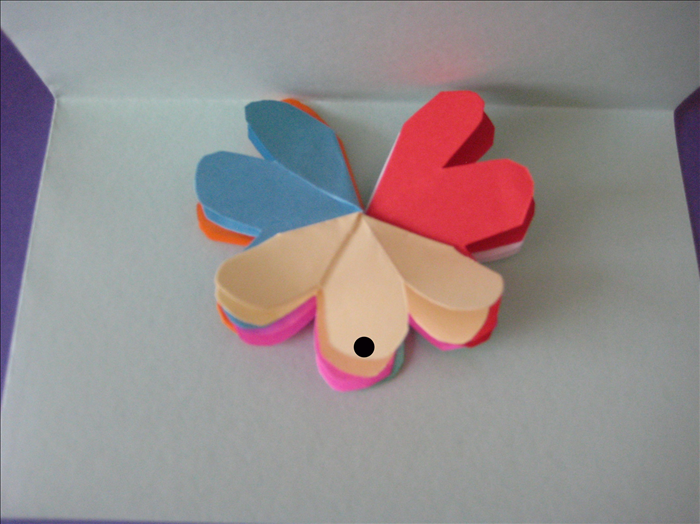 Fold you card in half.

Lift up one side of your card.
Place a dot of glue on the middle petal on the front and  the middle petal on the back- you are placing glue only where they touch the card.

Align the flower to the center crease of the card. 
Close the card and press down
Wait for the glue to dry completely
