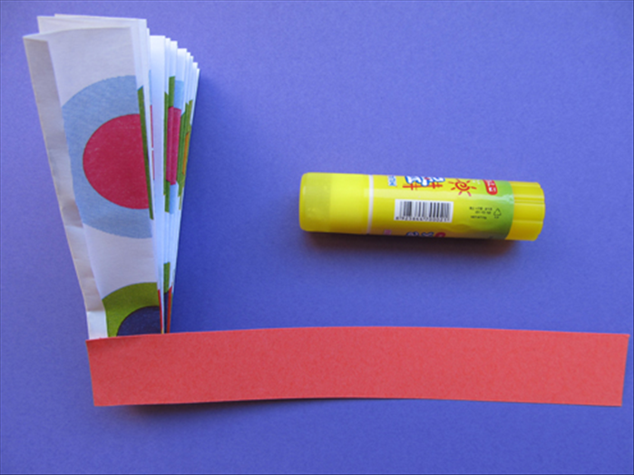 Align the small strip of paper with the side and bottom of the folded paper
Glue it in place
