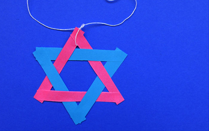 Put some glue at the top where the 2 triangle meet to hold them in place.

Your star of David is ready to hang alone or make many more to put on string for a garland.
