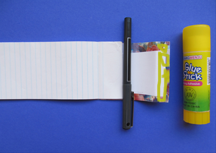 Flip it over again.
  Put glue on the folded area. Place your pen so that it is at the top of the memo paper.
