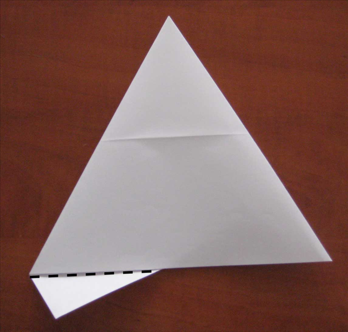 Flip the paper over to the back side.
Fold the small piece sticking out at the bottom over the edge.
Unfold it and then refold it but stick it in between the layers.
