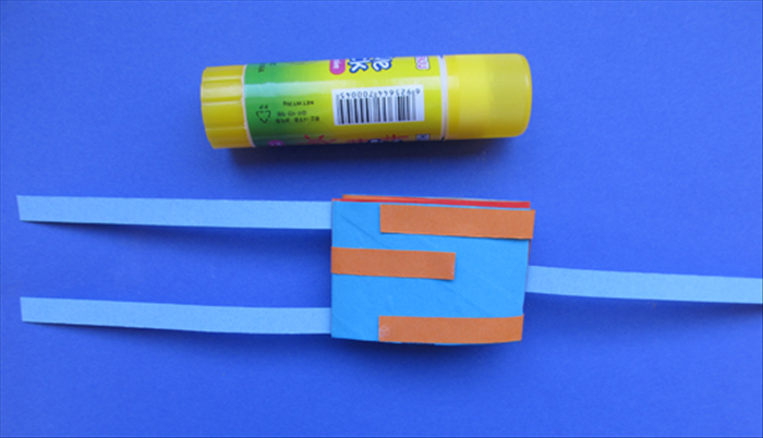 Bring the strips from the bottom tube up and over and to the opposite side. Glue them in place.