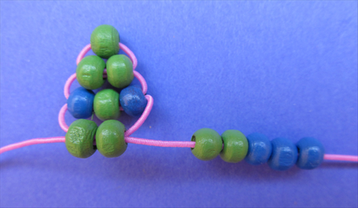 Now we will make the legs.
Insert 2 green beads and 3 blue beads on the right string.
