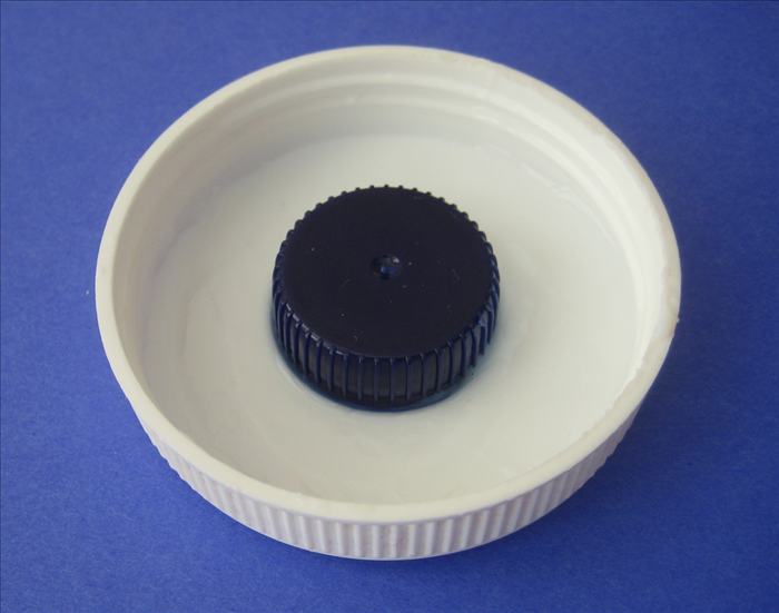 Place the cap into the glue and swirl it around to make sure it is generously coated on the bottom