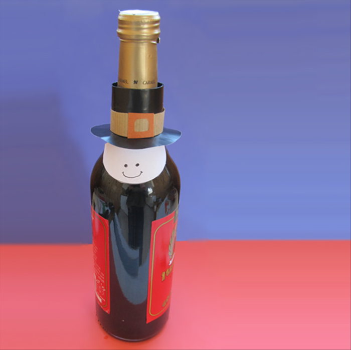Put glue on the ends of the straight edge of the half circle and wrap them onto the bottle, underneath  the hat.
Happy Thanksgiving!
