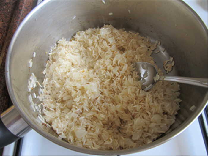 Add the uncooked rice to the pot and stir and fry until it is golden brown