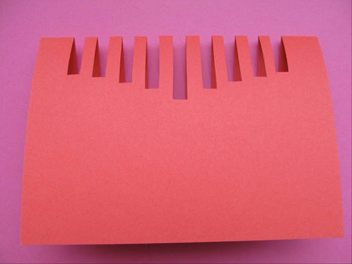Bring the top of the paper down to fold it in half and give the folded end a sharp crease.