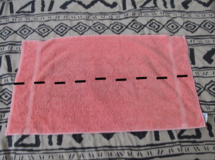 Place the hand towel so that the long sides are at top and bottom
Bring the top edge down to fold it in half

