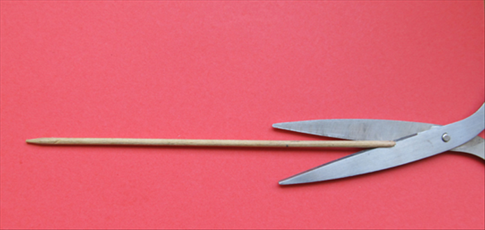 <p> Carefully make a slit in the flat end of the skewer with a scissor.</p>