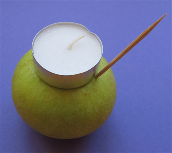Place the candle on the center top of the apple.
 Insert a toothpick at the edge of the candle.
 Drag it around the outside of the candle to mark the shape.