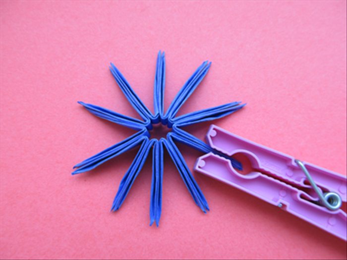 When the glue has dried remove the rubber band.

Spread the pieces open and bring the ends around.
Glue them together – ¼ of the way from the folded end

Hold it together with a clothespin until the glue is completely dry
