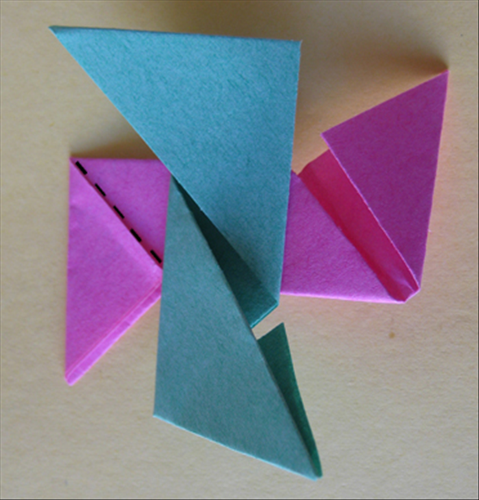 <p> Flip the first paper over to the back side. Rotate the second paper and place it on top of the first in the center as shown in the picture. Fold the paper on the bottom along the flap</p>