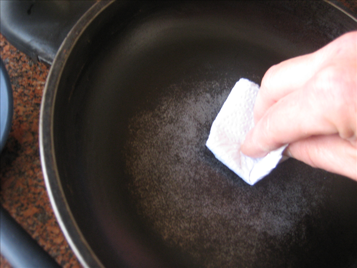 Put very little butter or margarine in the frying pan and  spread it to coat with a paper towel. 
Very little is needed to make pancakes and you will not have to add anymore while cooking all the pancakes.
Heat the frying pan over medium heat.