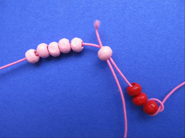 Insert the string through the petal bead  closest to the spacer beads - through the side closest to the spacer beads