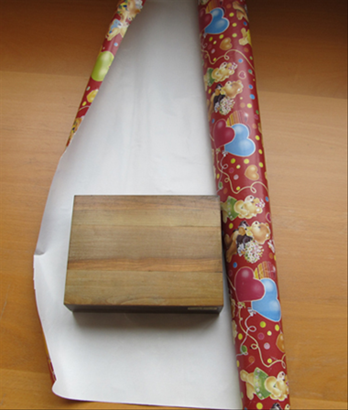 Unroll some paper and place your present upside down near the edge.