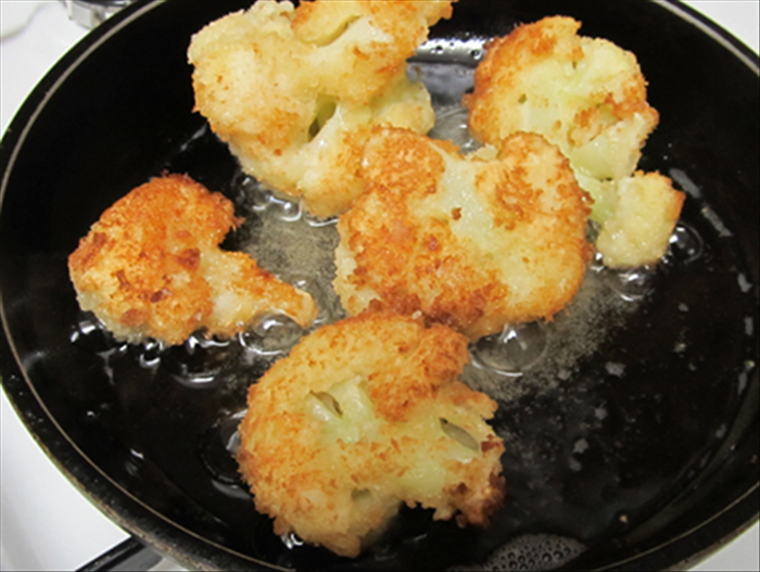 Heat the oil on a medium low heat.
Fry the cauliflower until golden brown  and turn the pieces  to fry the bottom sides.  
