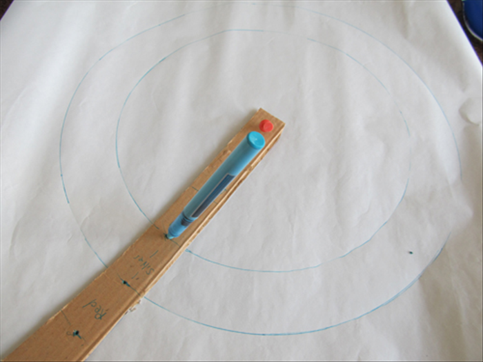 <p> Turn the sliver or white paper colored side face down.</p> 
<p> Place the pin or nail through the bottom hole and through the center of the paper.</p> 
<p> Insert the pen tip in the bottom hole below the word silver. Rotate and make a circle.</p> 
<p> Place the pen in the top hole above the word silver. Rotate and make another circle.</p> 
<p> This is the silver ring. Cut it out along the lines.</p>