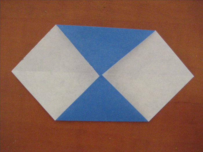  The colored side of the paper should  be on the bottom.
 Bring the top and bottom points up to the center crease you just made in the last step.