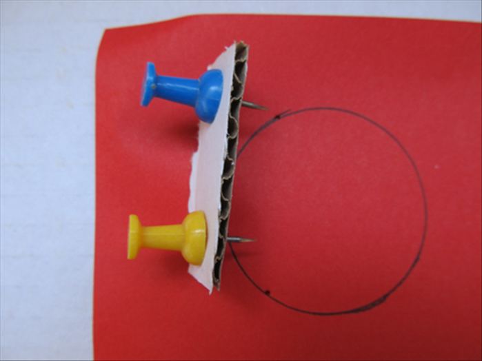 Cut a strip of cardboard or sturdy paper.
Insert the pins at a distance a little more than ½ of the circle.

